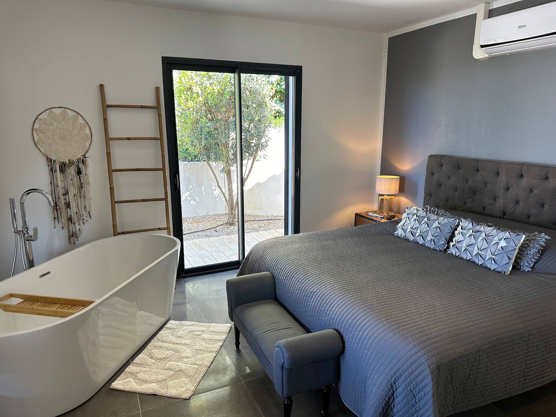 La suite, sa baignoire îlot et son lit double, ouverte sur le patio arboré