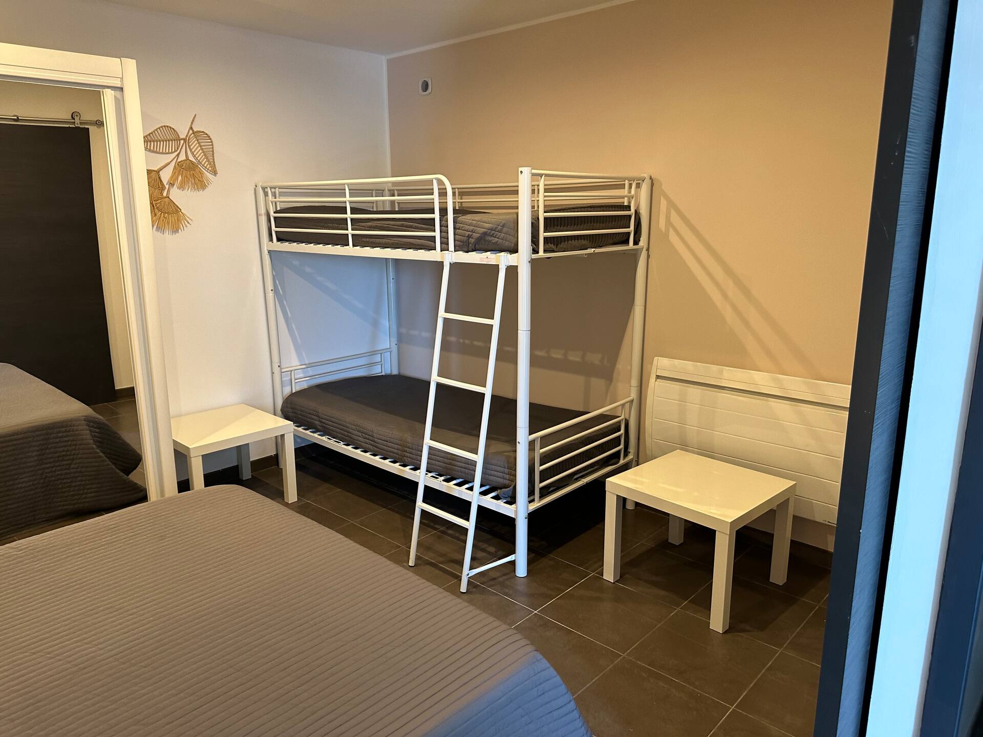 Chambre équipée de lits superposés en métal blanc, et son lit double