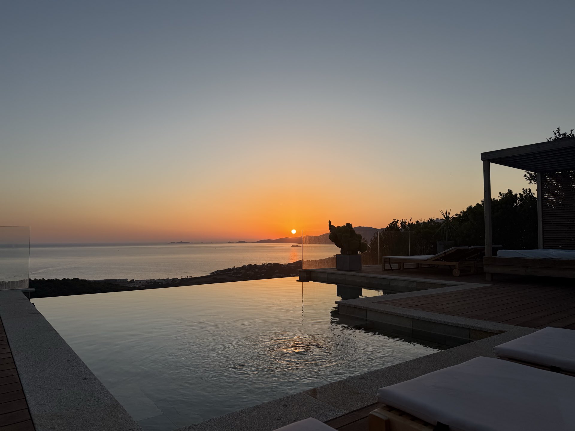 La piscine à débordement au coucher du soleil, le disque touchant l’horizon au-dessus du golfe