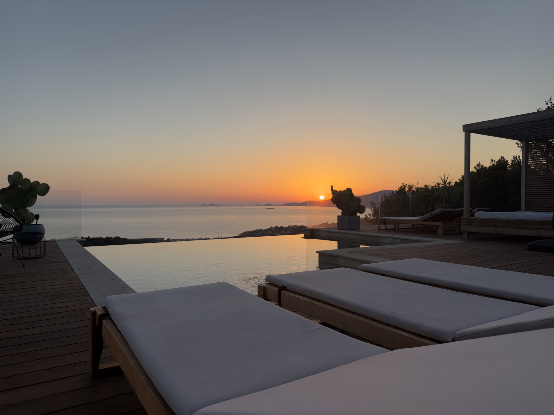 Le soleil touche l’horizon marin, la piscine à débordement au premier plan