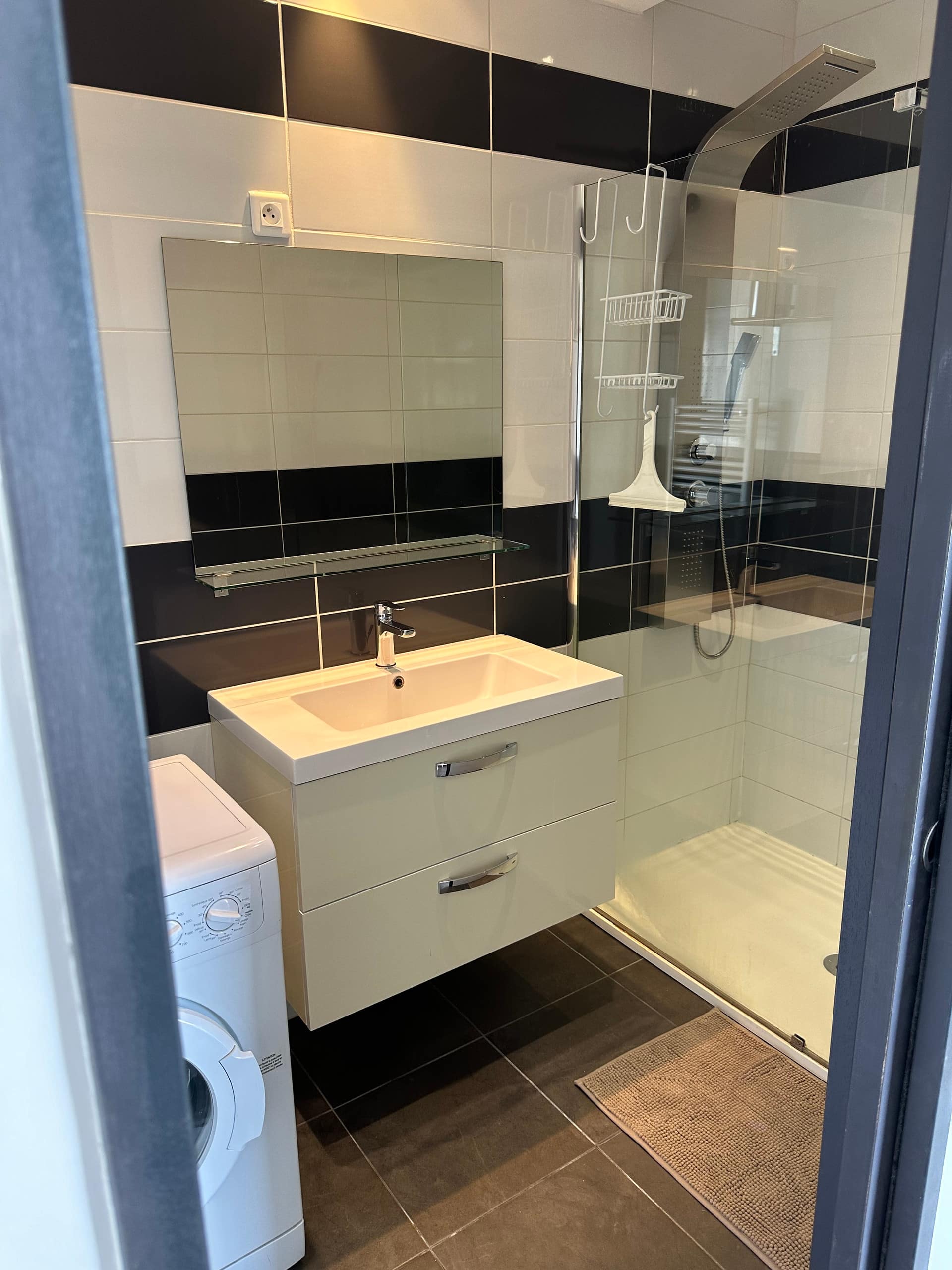 Salle d’eau carrelée de noir et blanc, vasque et douche à l’italienne