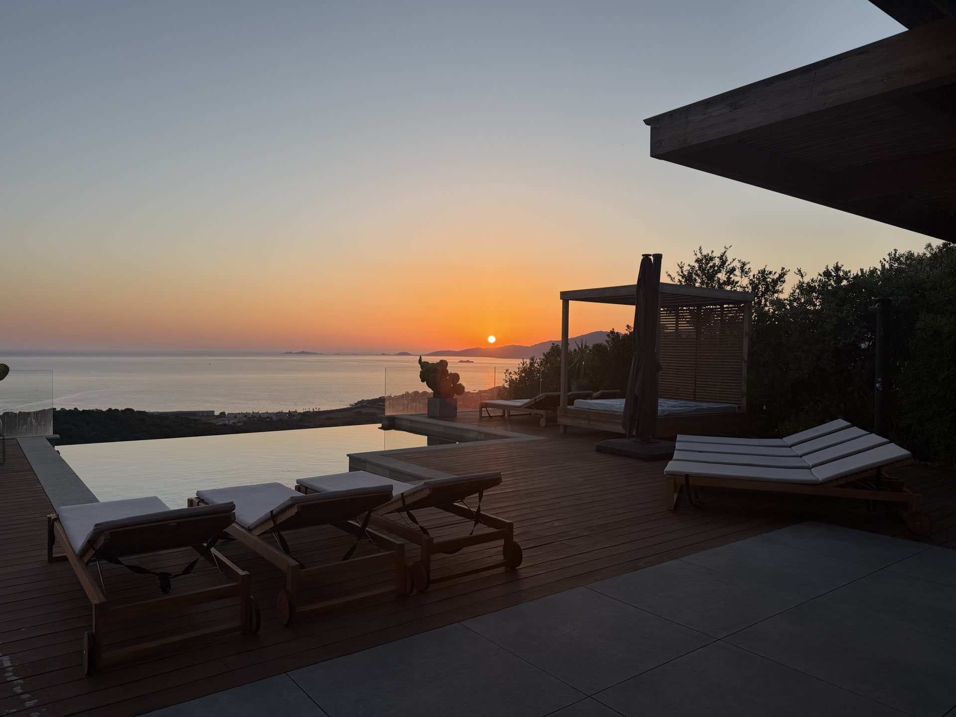 Coucher de soleil sur le golfe depuis la terrasse, les transats tournés vers l’horizon